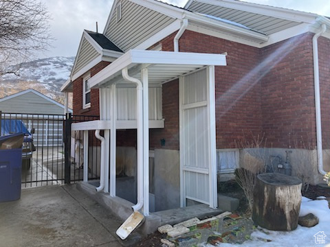 View of side of home featuring an outbuilding, a gate, fence, and brick siding