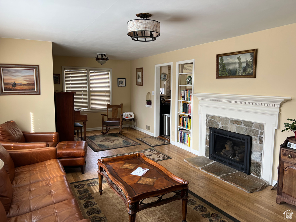 Living room with built in shelves, a fireplace, baseboards, and wood finished floors