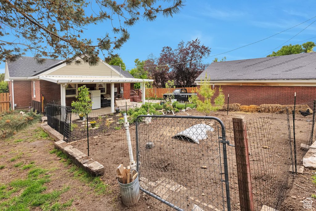 View of side of home with a gate, a fenced backyard, brick siding, and a patio area