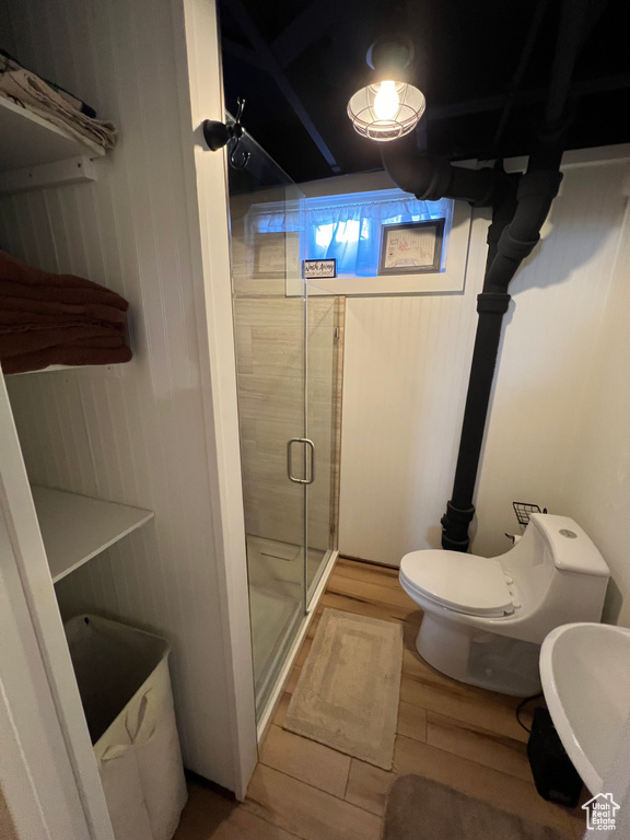 Bathroom with toilet, wood finished floors, and a shower stall