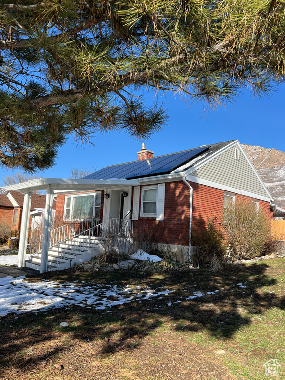 Ranch-style home with brick siding, solar panels, and a chimney