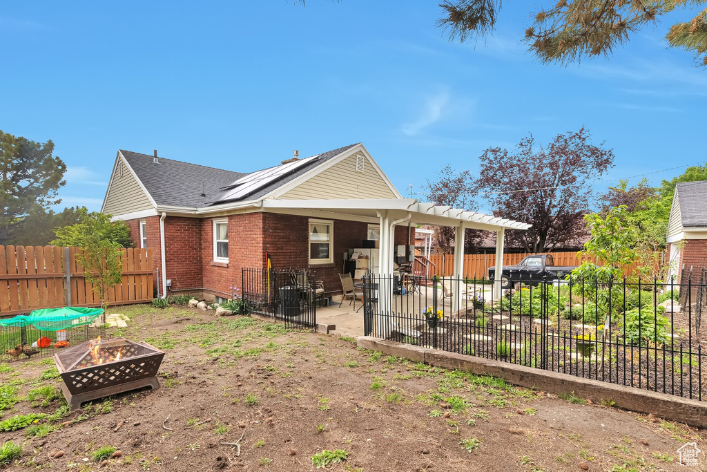 Back of property with an outdoor fire pit, a patio area, brick siding, a fenced backyard, and a shingled roof