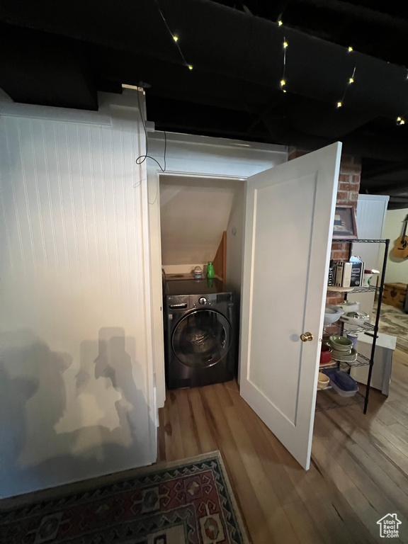 Washroom with laundry area, washer / dryer, and wood finished floors
