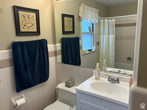 Bathroom with toilet, tile walls, and a shower with shower curtain