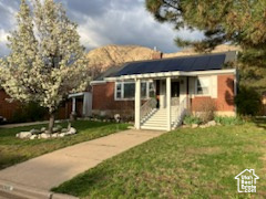 View of front of property featuring roof mounted solar panels, a front lawn, and a mountain view