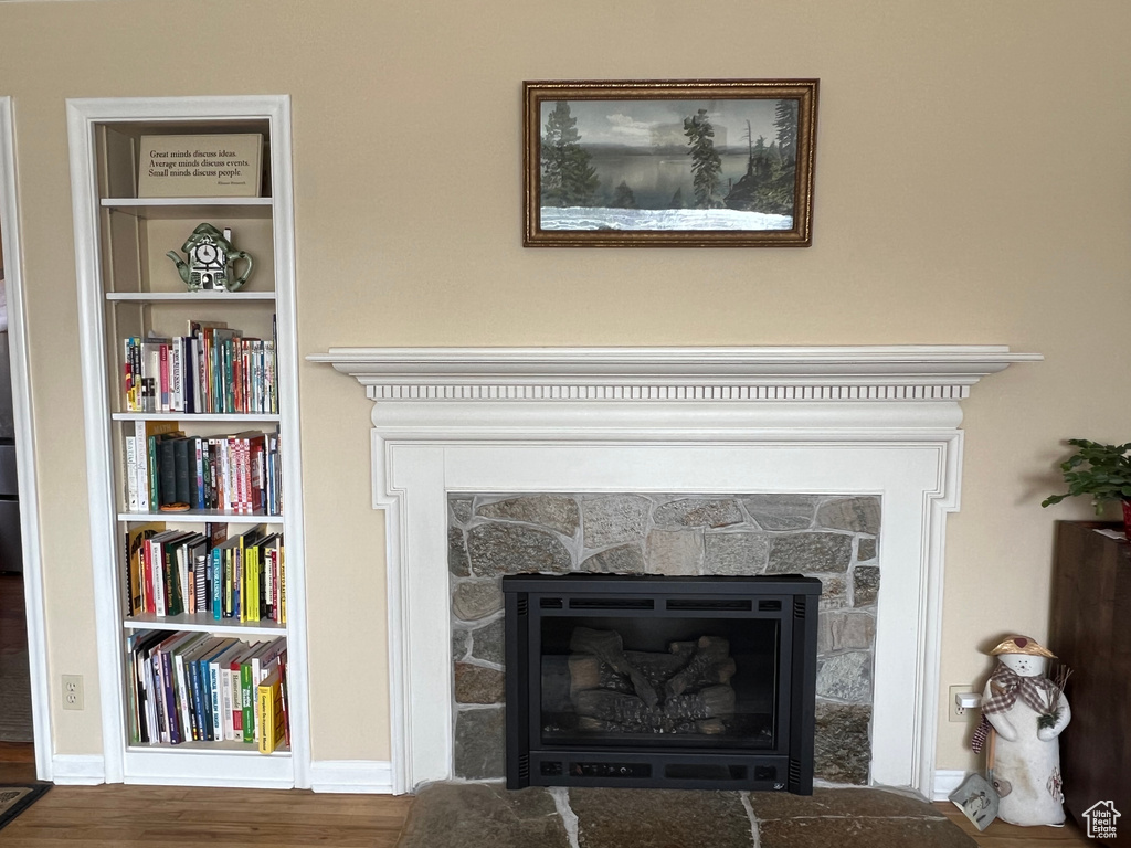 Details with built in features, baseboards, wood finished floors, and a fireplace