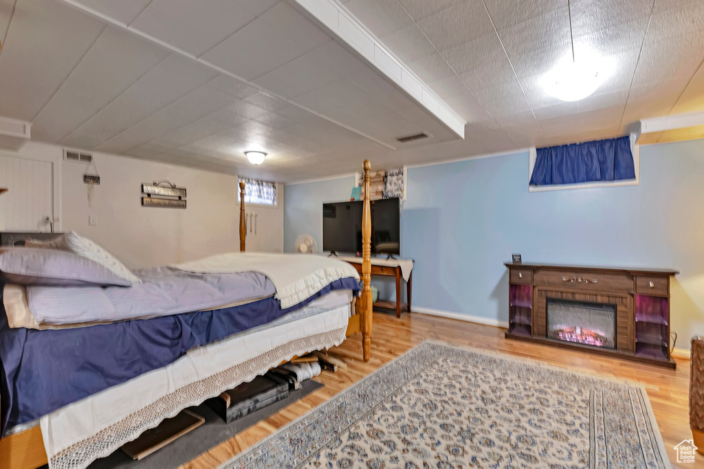 Bedroom featuring wood finished floors, a lit fireplace, and baseboards
