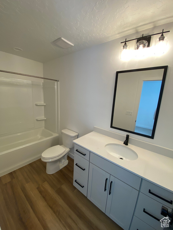 Full bathroom featuring toilet, a textured ceiling, wood finished floors, shower / bath combination, and vanity