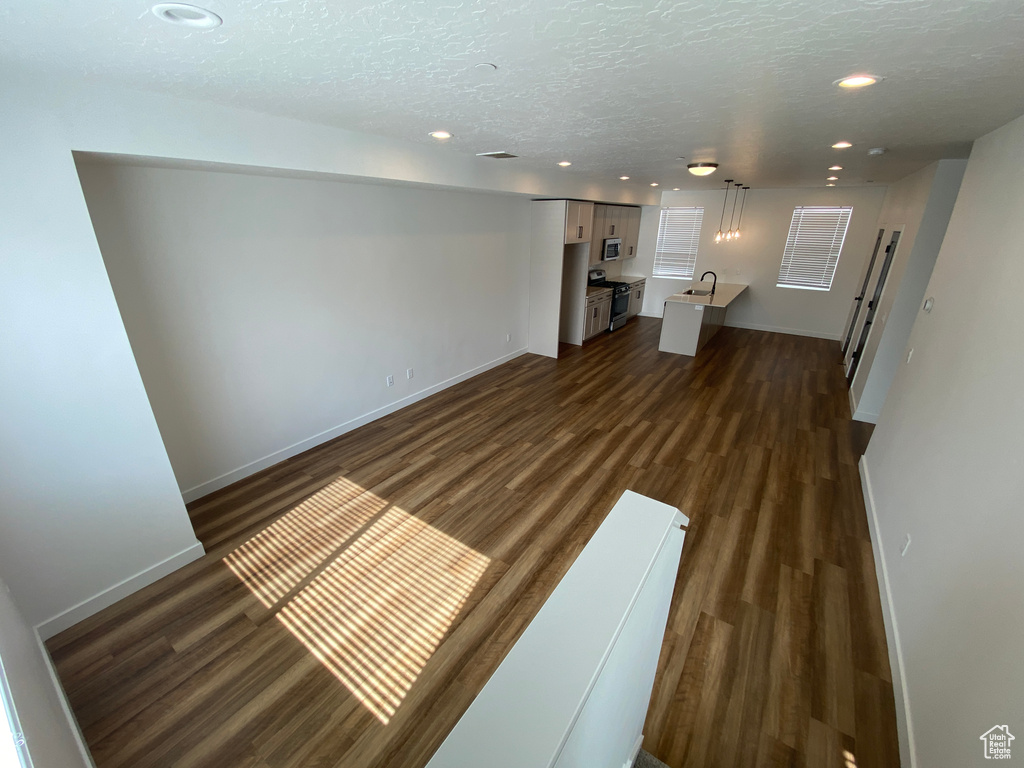 Unfurnished living room with recessed lighting, dark wood-style floors, baseboards, and a textured ceiling