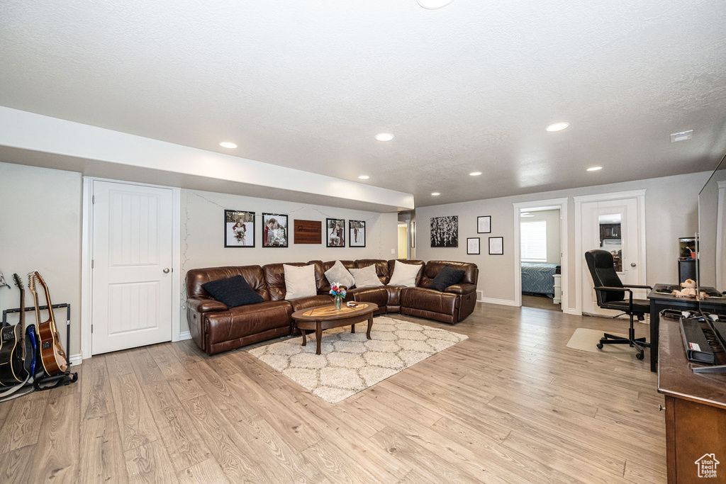 Living room featuring baseboards, recessed lighting, a textured ceiling, and light wood-style floors