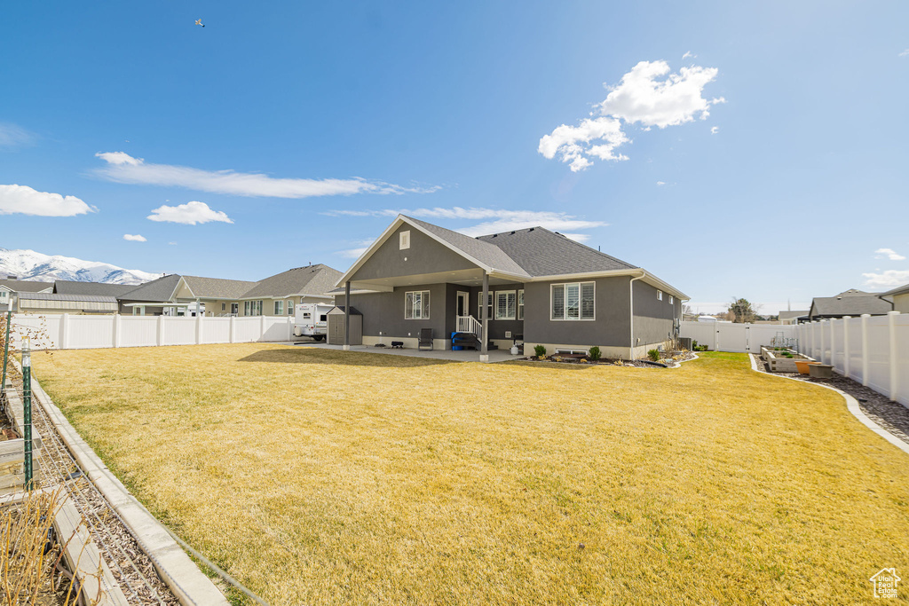 Back of property with roof with shingles, a lawn, stucco siding, a fenced backyard, and a patio area