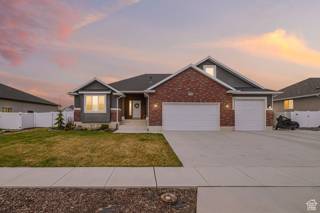 View of front of property featuring a front yard, a gate, fence, driveway, and a garage