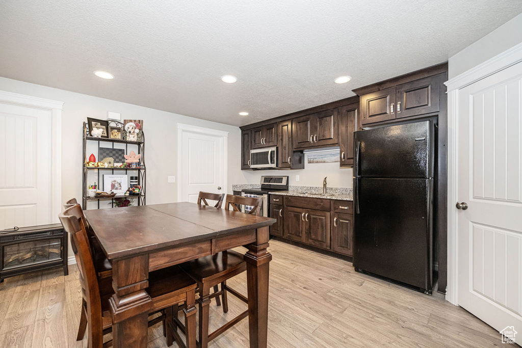 Kitchen with a sink, recessed lighting, stainless steel appliances, dark brown cabinetry, and light wood finished floors