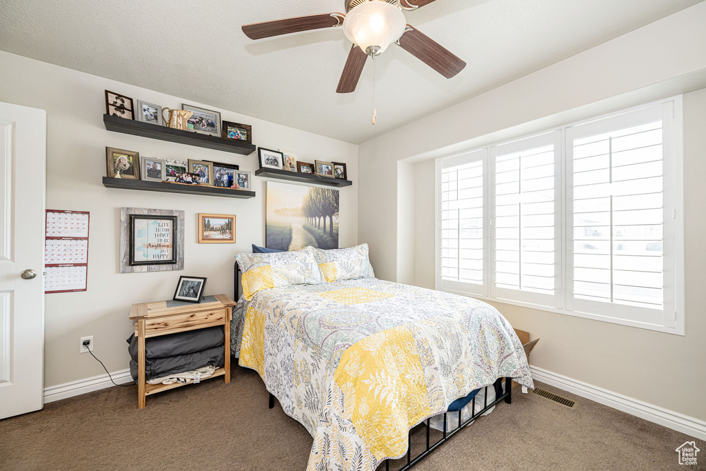 Carpeted bedroom with visible vents, ceiling fan, and baseboards