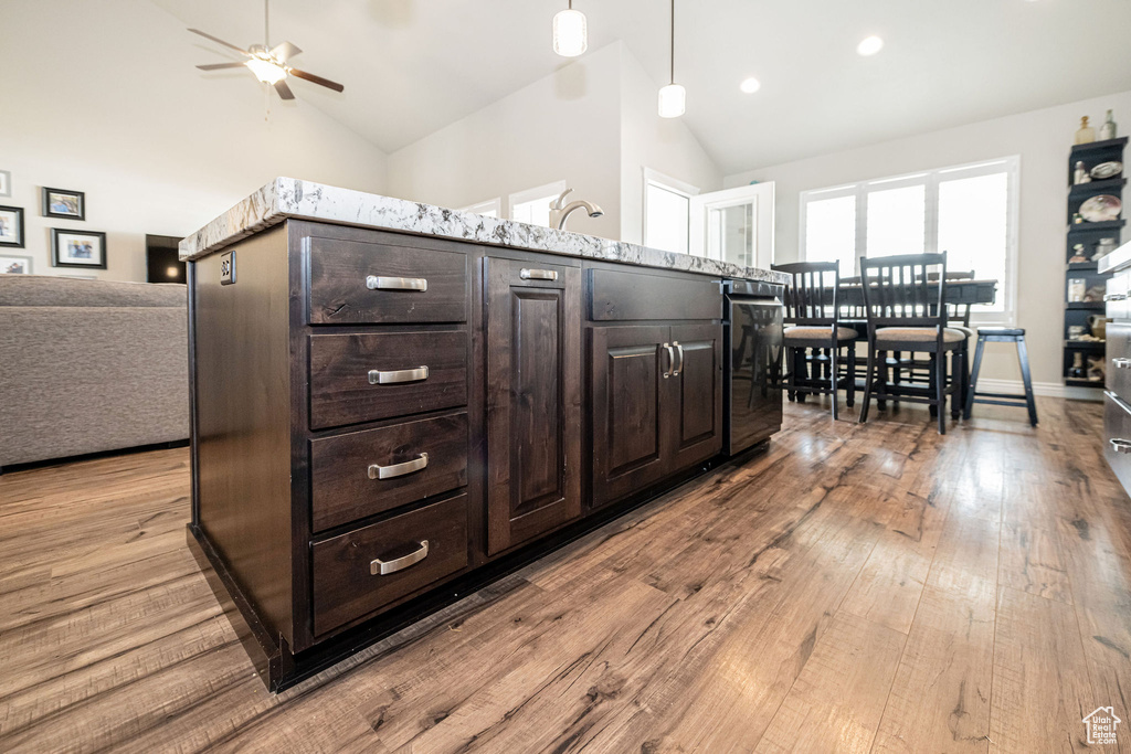 Kitchen featuring hardwood / wood-style flooring, a ceiling fan, open floor plan, and high vaulted ceiling
