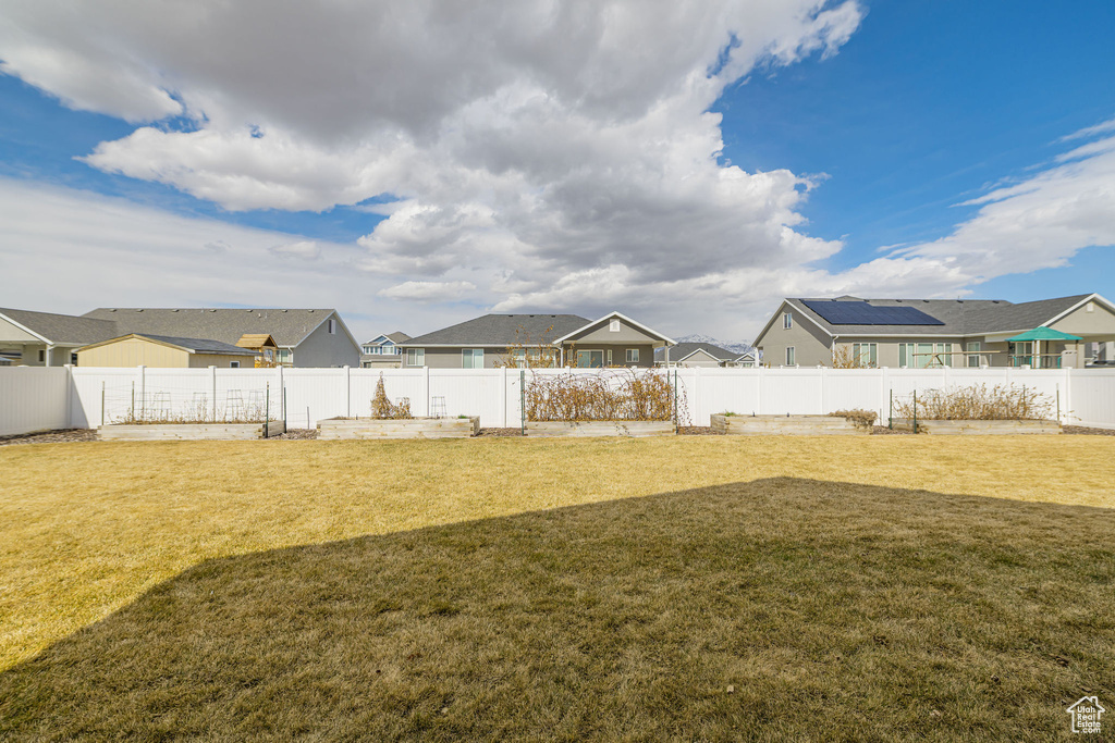View of yard featuring a garden, a fenced backyard, and a residential view