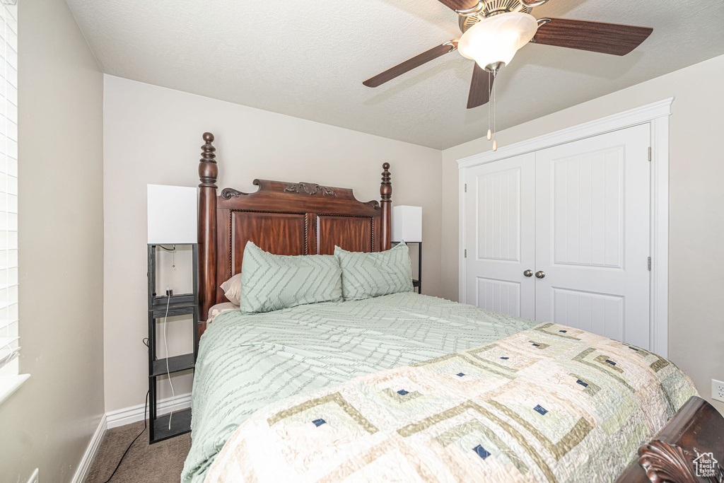 Carpeted bedroom with a textured ceiling, baseboards, a closet, and ceiling fan