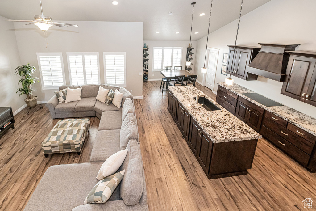 Living room with light wood finished floors, baseboards, lofted ceiling, recessed lighting, and a ceiling fan
