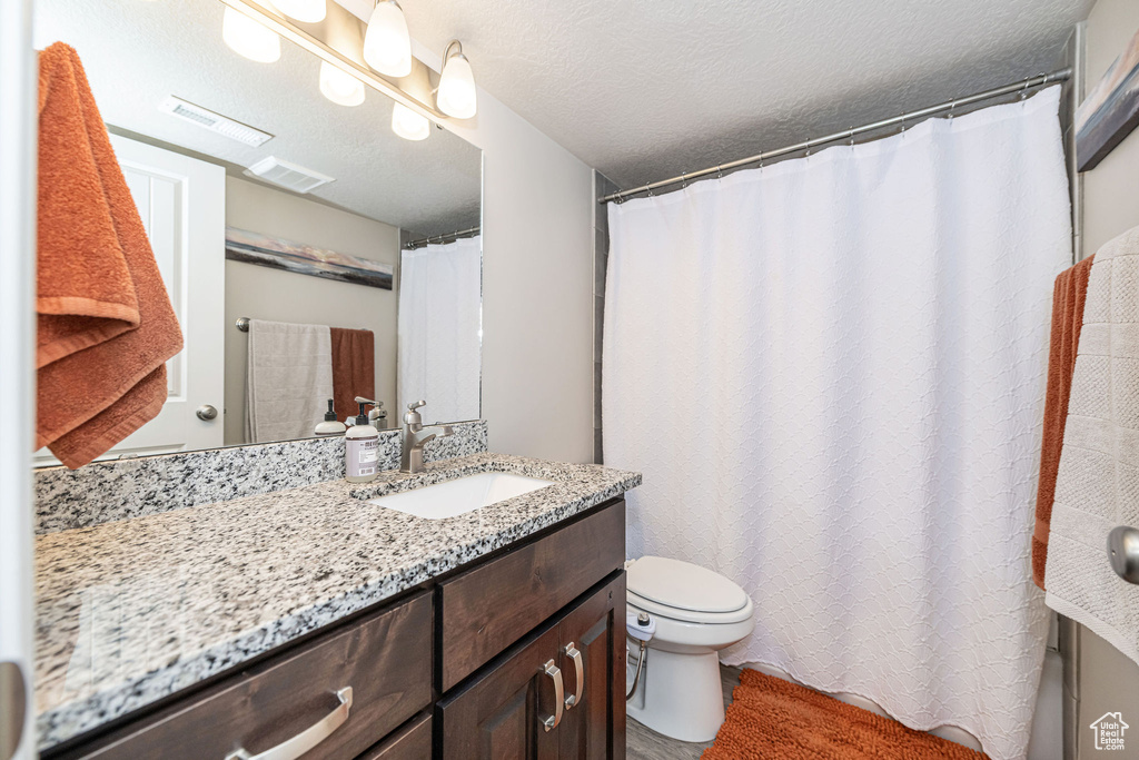 Bathroom with visible vents, a textured ceiling, vanity, and toilet