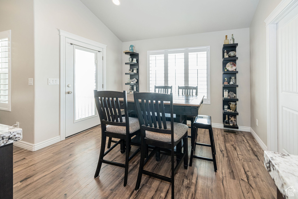 Dining space featuring vaulted ceiling, wood finished floors, and baseboards