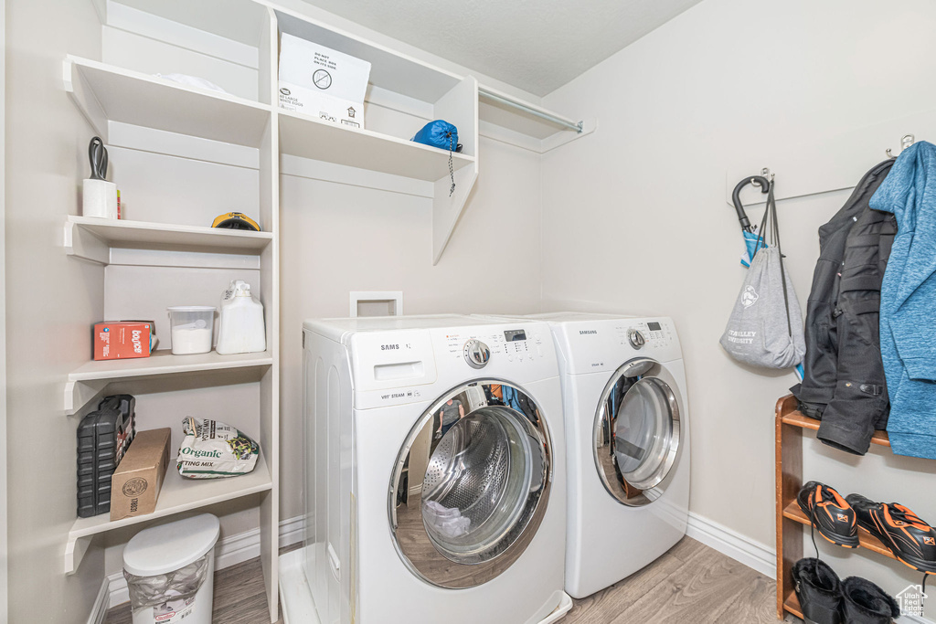 Laundry area featuring laundry area, light wood-style flooring, baseboards, and washing machine and clothes dryer