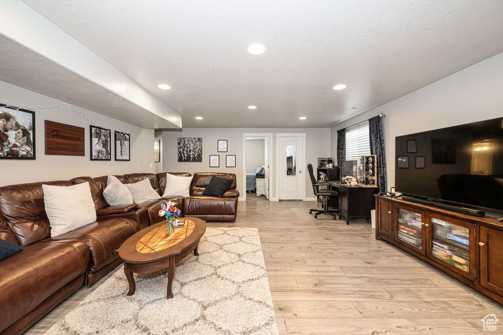 Living room with recessed lighting, a textured ceiling, and light wood-style flooring