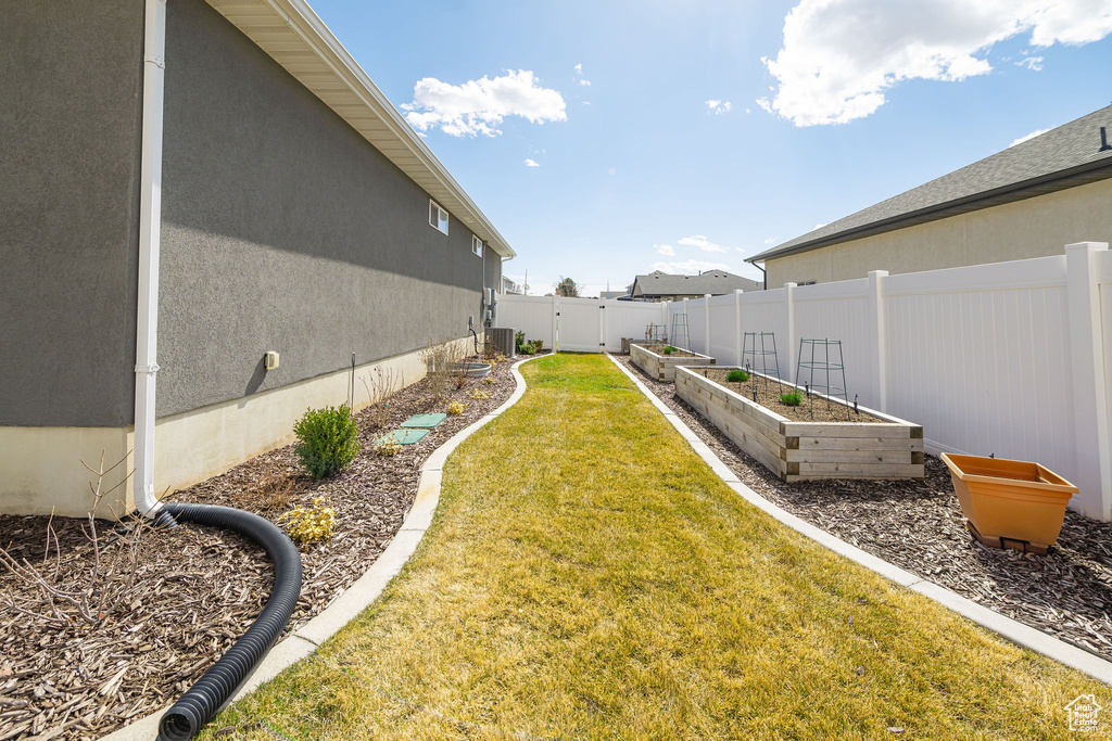 View of yard with central AC unit, a vegetable garden, and fence