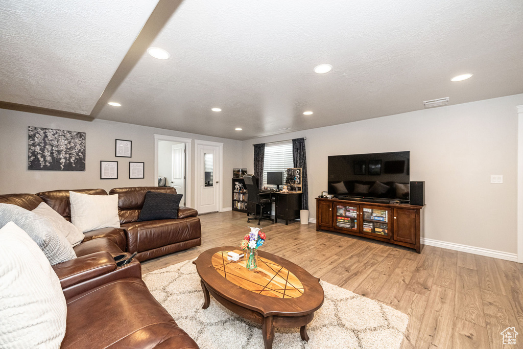Living area featuring recessed lighting, a textured ceiling, and light wood-style flooring
