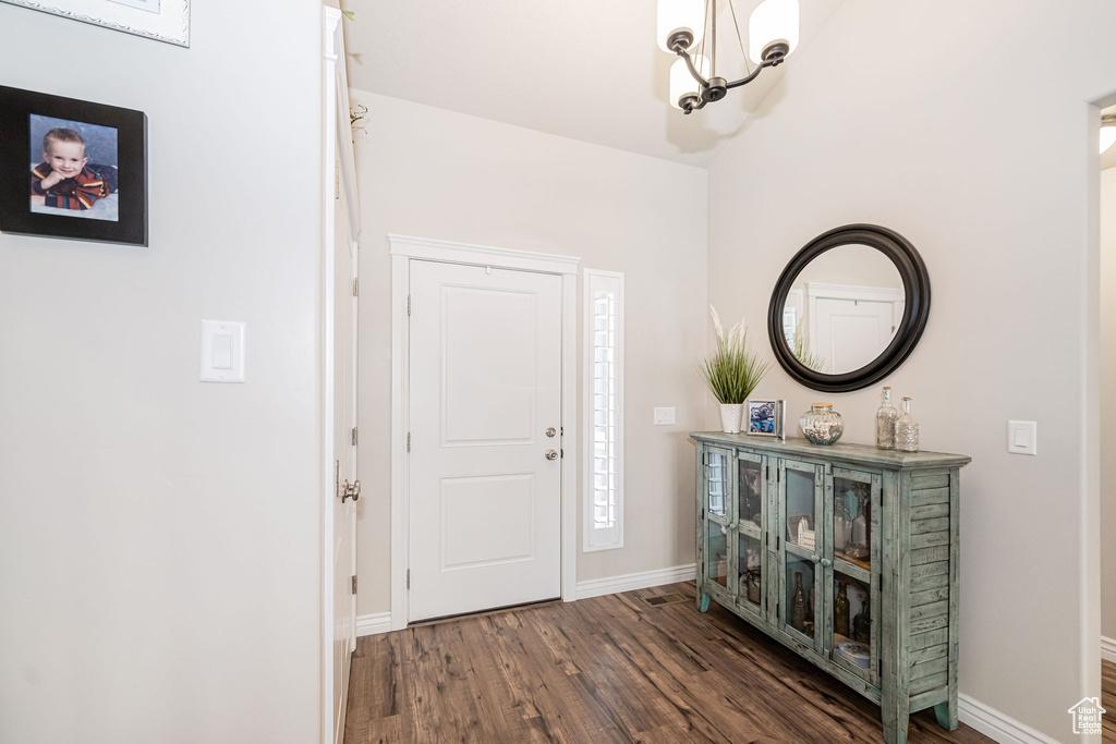 Foyer with baseboards, a notable chandelier, and wood finished floors