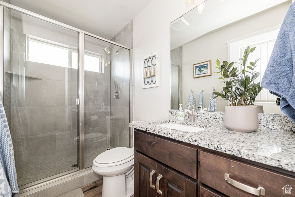 Bathroom with visible vents, toilet, a stall shower, and vanity
