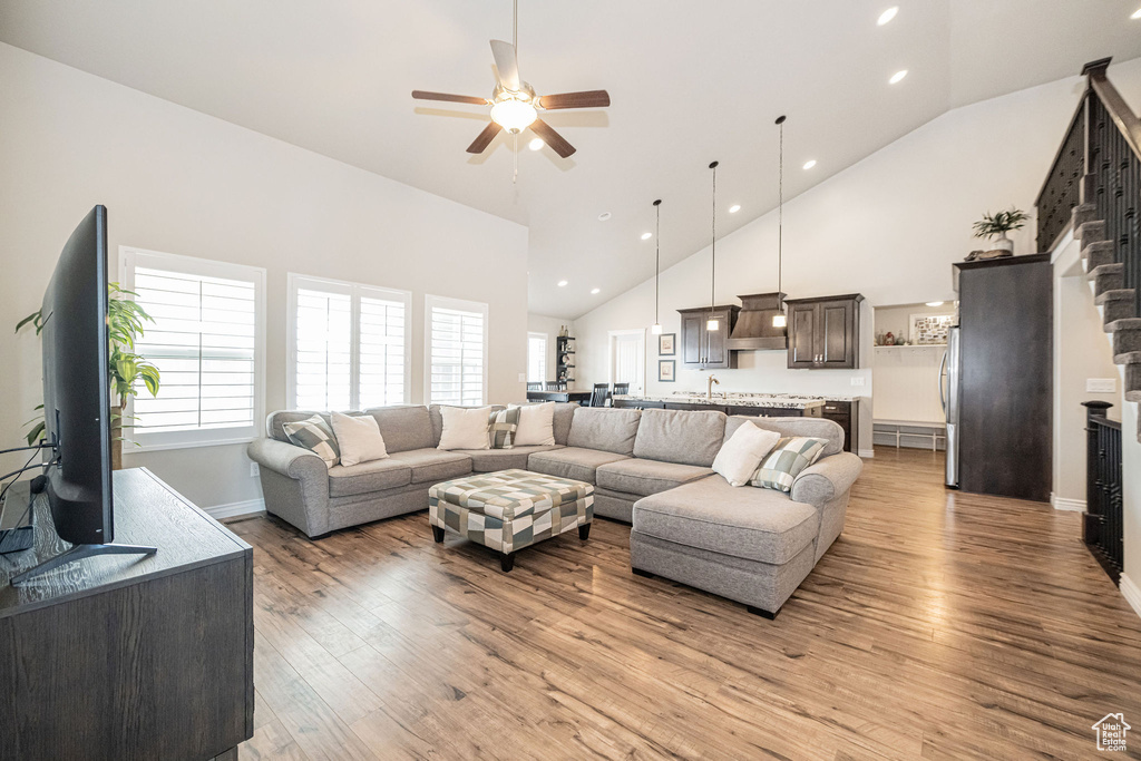 Living room featuring a ceiling fan, baseboards, high vaulted ceiling, recessed lighting, and light wood-style floors