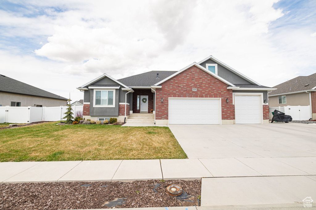 Ranch-style home featuring brick siding, concrete driveway, a front yard, and fence
