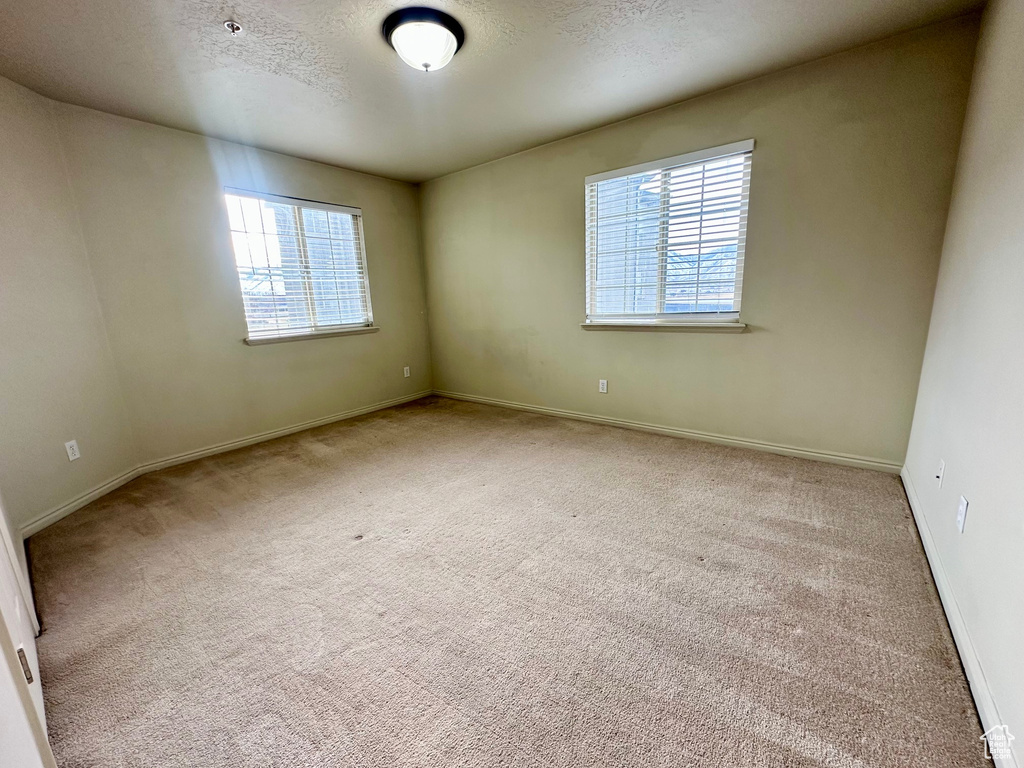 Carpeted empty room featuring baseboards and a textured ceiling