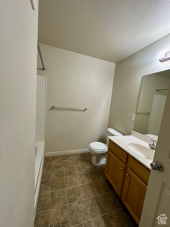 Full bathroom with vanity, baseboards, a textured ceiling, tile patterned floors, and toilet