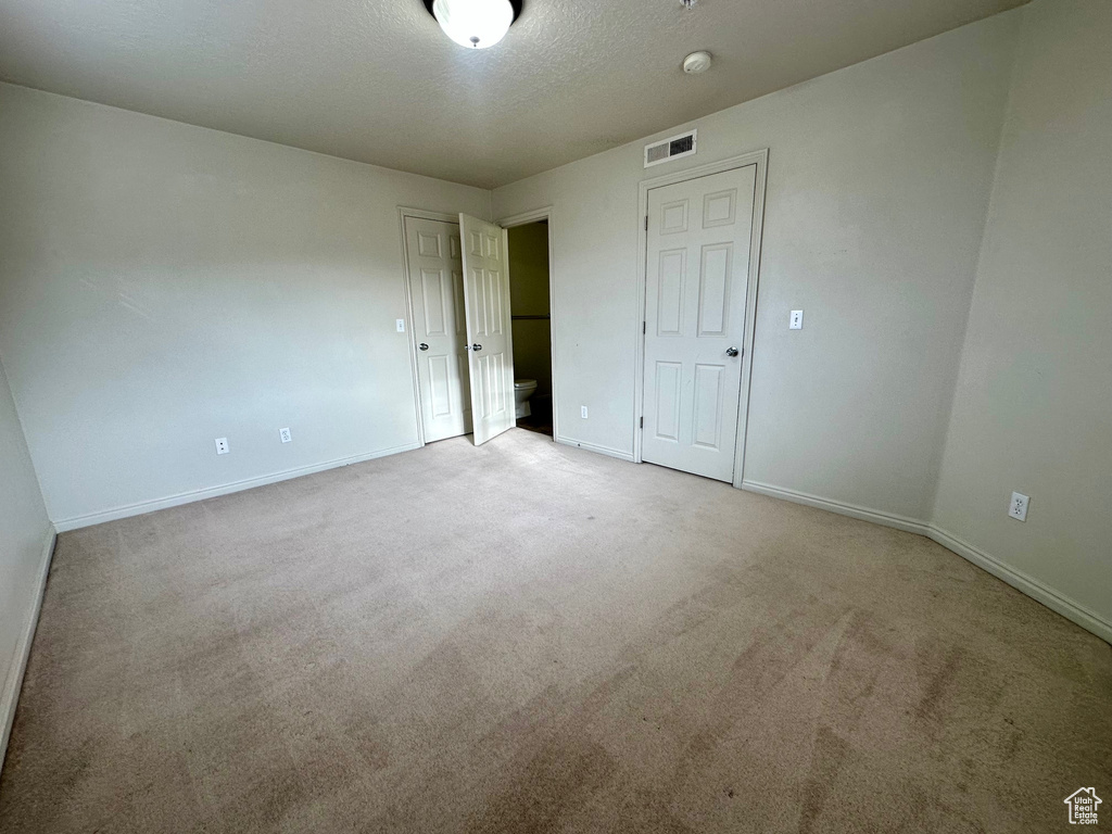 Unfurnished bedroom featuring visible vents, baseboards, carpet, and a textured ceiling