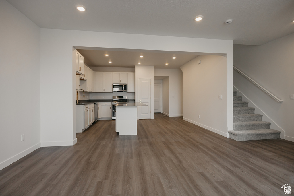 Kitchen featuring a sink, dark countertops, dark wood finished floors, recessed lighting, and appliances with stainless steel finishes