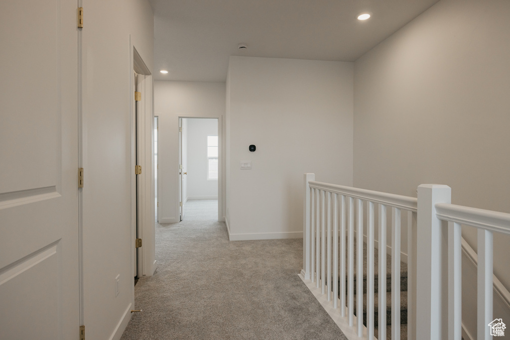 Corridor featuring an upstairs landing, recessed lighting, light colored carpet, and baseboards