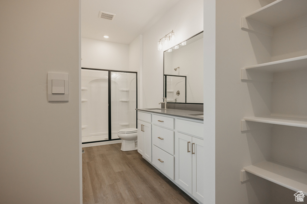Bathroom with vanity, wood finished floors, visible vents, walk in shower, and toilet