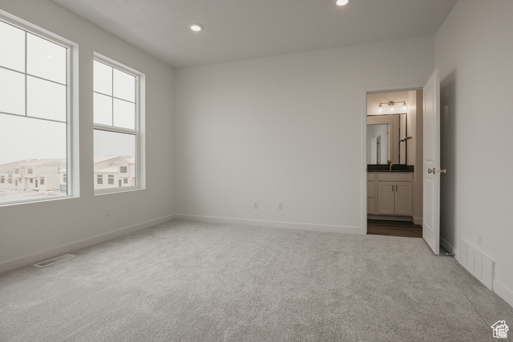 Unfurnished bedroom with recessed lighting, visible vents, ensuite bathroom, and carpet flooring