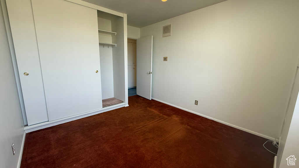 Unfurnished bedroom featuring dark colored carpet and baseboards