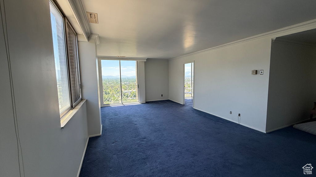 Unfurnished room with dark carpet, baseboards, and crown molding