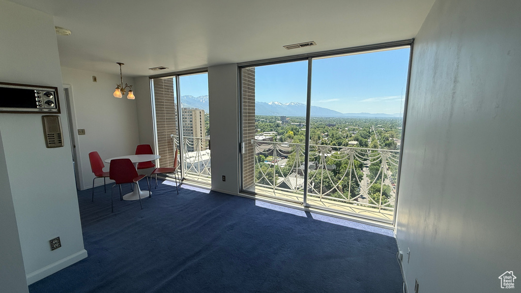 Empty room featuring a mountain view, floor to ceiling windows, baseboards, and a chandelier