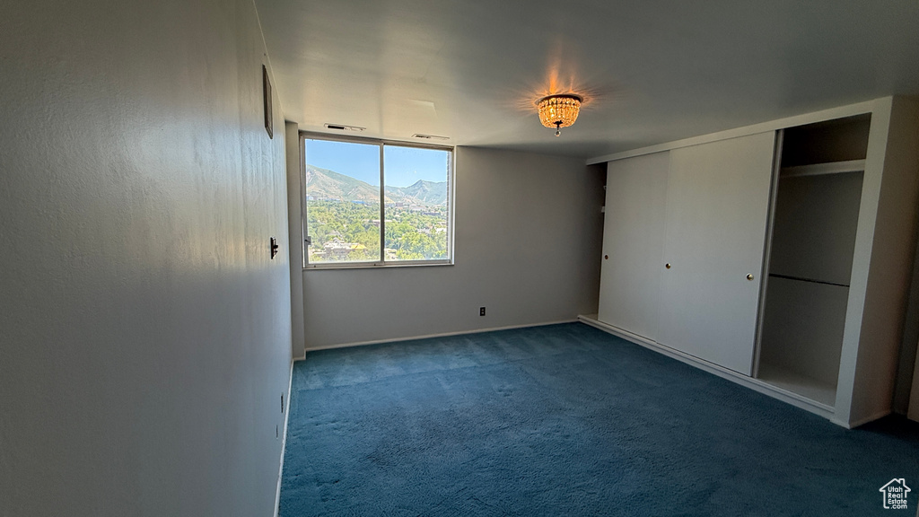 Unfurnished bedroom with dark colored carpet, baseboards, a mountain view, and a closet