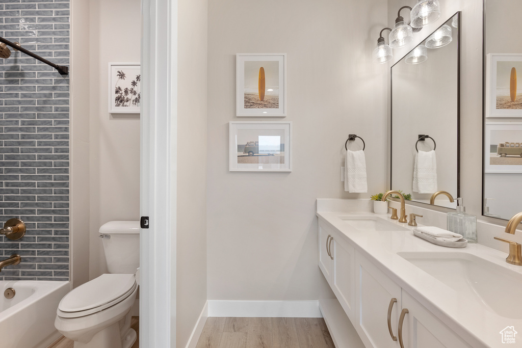 Bathroom with a sink, toilet, wood finished floors, and double vanity