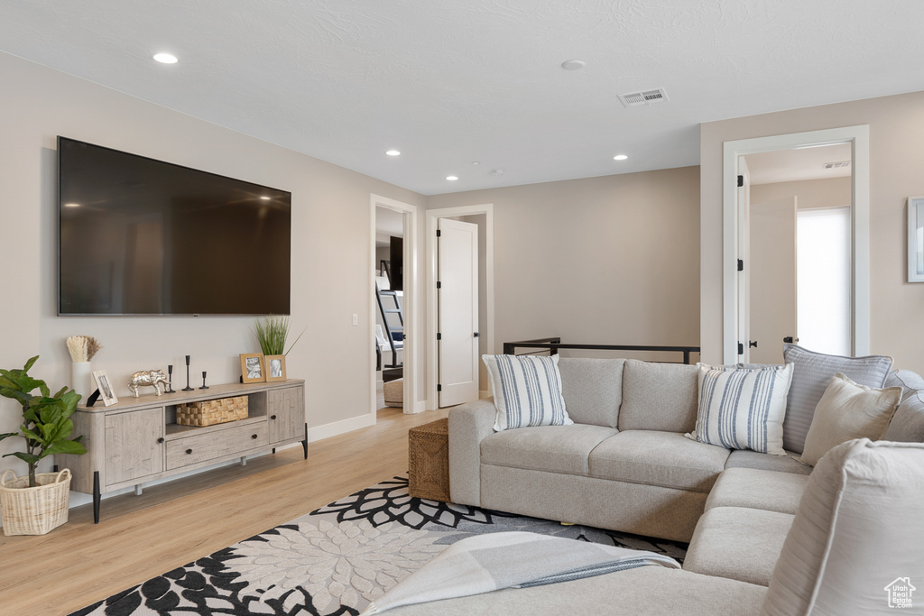 Living area featuring visible vents, recessed lighting, light wood-style floors, and baseboards
