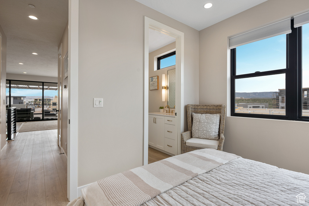Bedroom with ensuite bath, recessed lighting, and light wood-type flooring