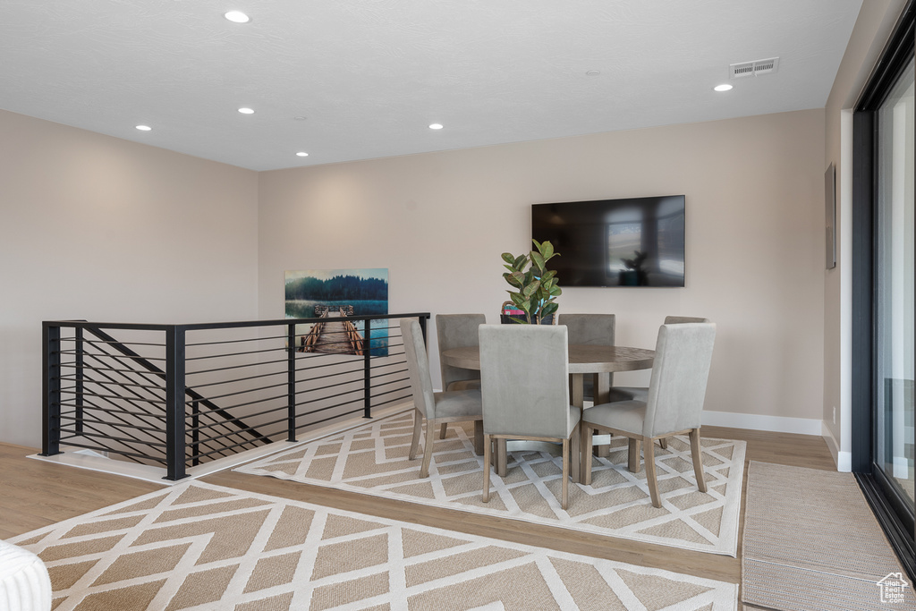 Dining room with wood finished floors, recessed lighting, visible vents, and baseboards