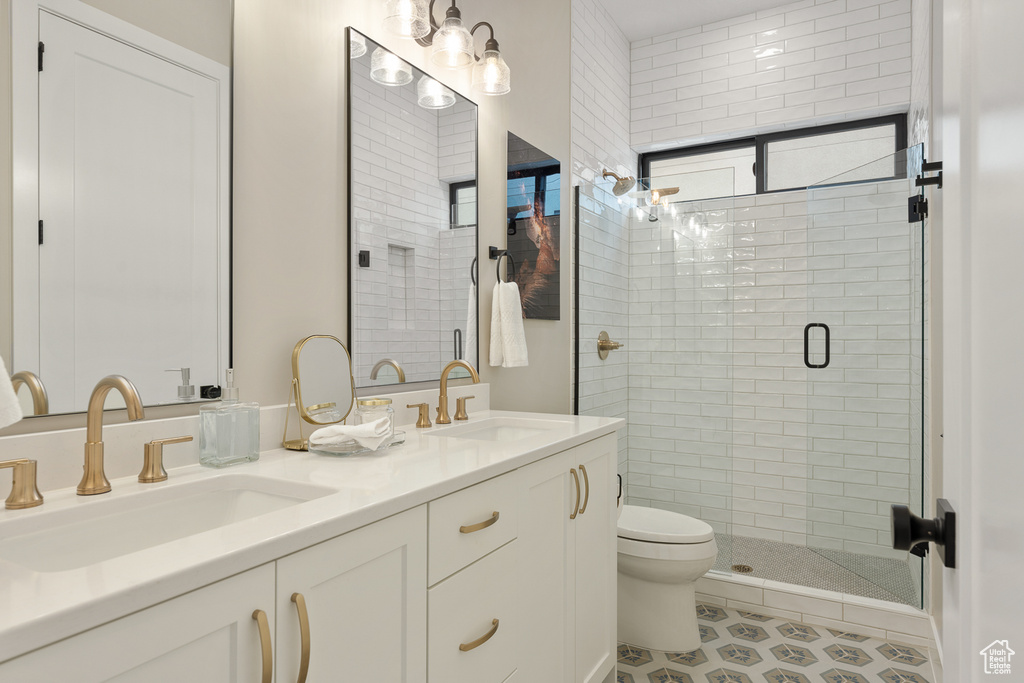 Bathroom with a sink, toilet, double vanity, and a shower stall