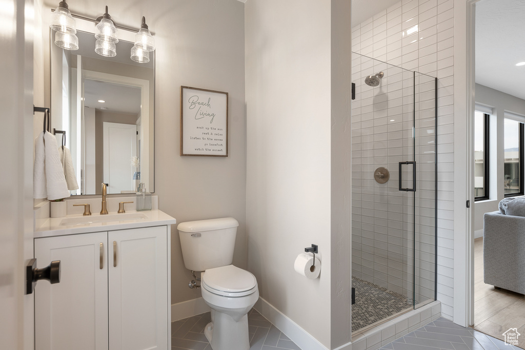Bathroom featuring vanity, a shower stall, toilet, and baseboards