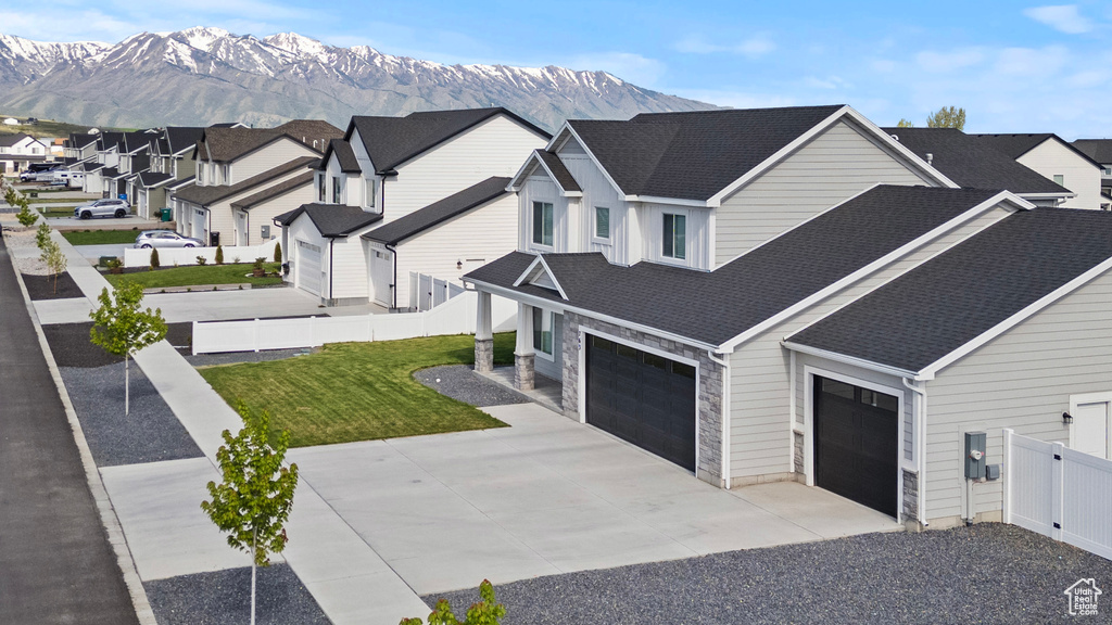 View of home's exterior with a mountain view, roof with shingles, driveway, and stone siding